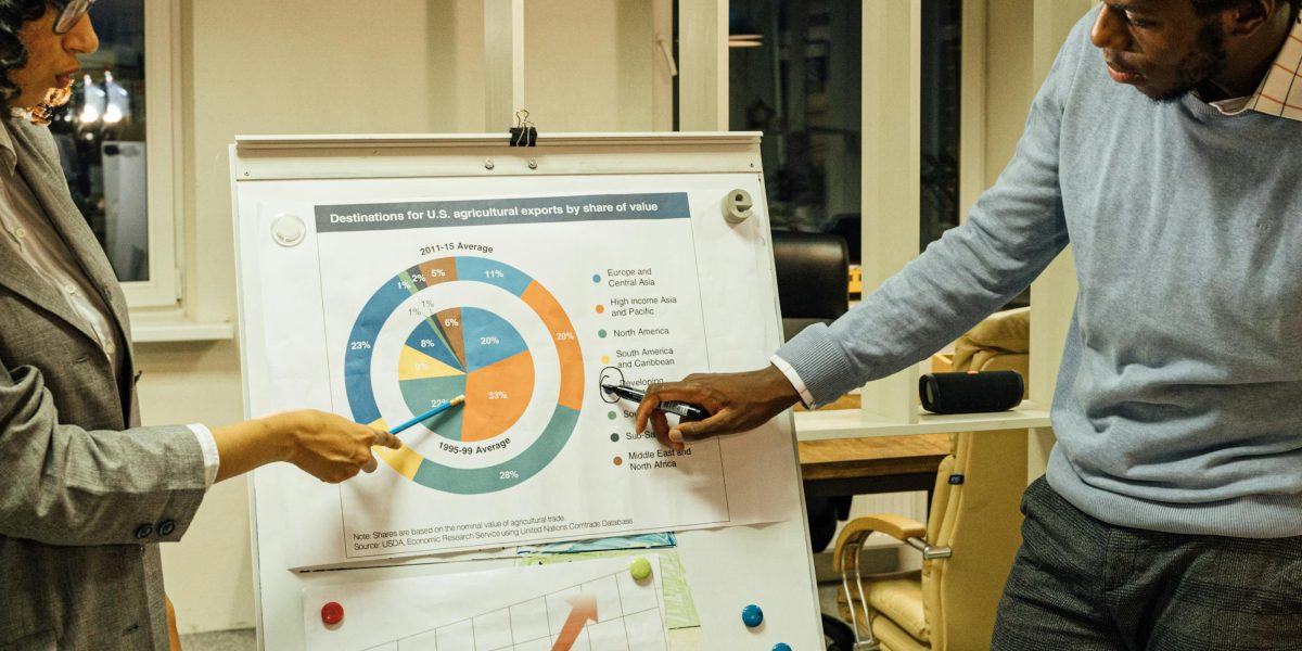 Two business professionals collaborating and researching market trends on a large screen in a modern office setting.