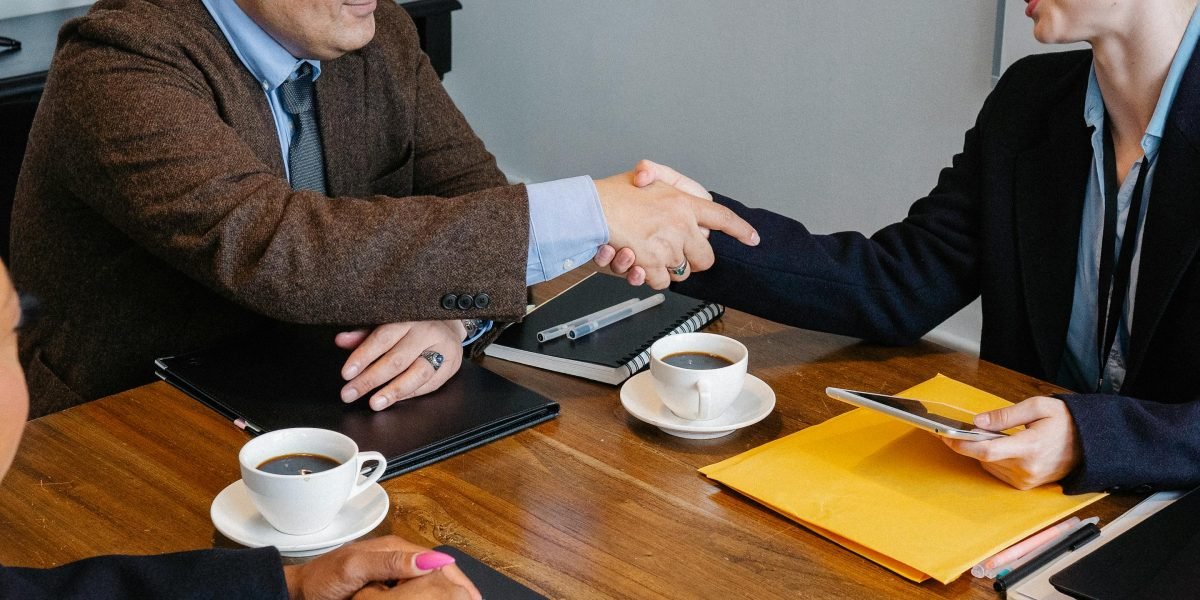 Two professionals shaking hands across a table, symbolizing a successful partnership and the trust built with an expert consultant in international real estate.