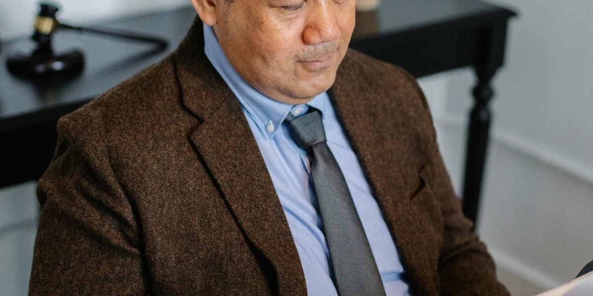 A professional meticulously reviewing legal and financial documents at an office desk.