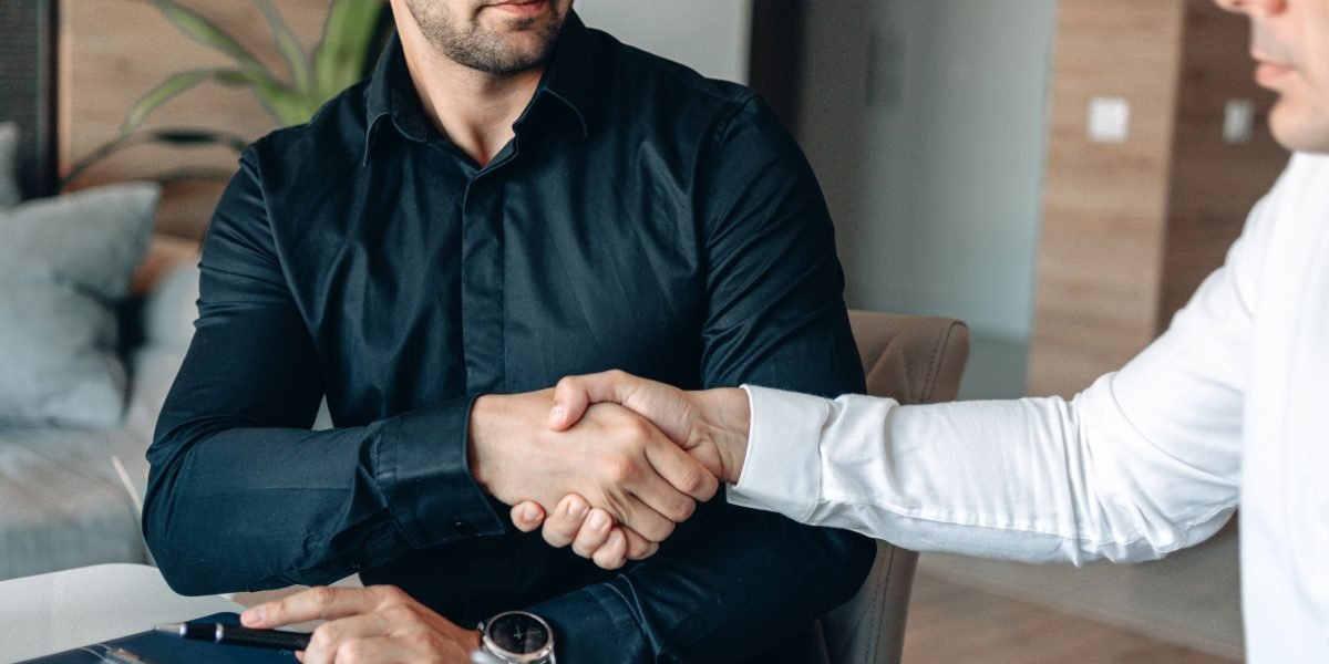 Two business partners engaged in a serious discussion, negotiating terms around a table, representing the complexities of commercial agreements.